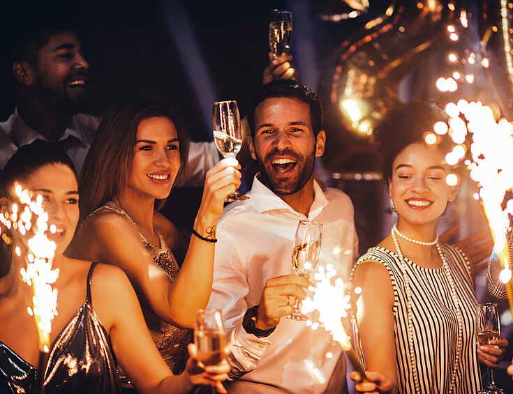 Gruppe von Menschen feiern Silvester mit Sekt und Wunderkerzen