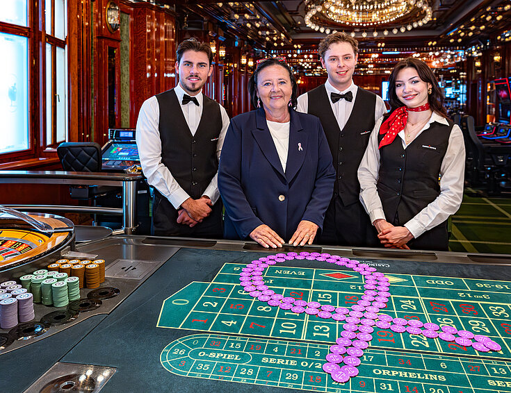 Pink Casino Night - Doris Kiefhaber Geschäftsführerin der Österr. Krebshilfe und der Aktion Pink Ribbon mit Croupière und Croupiers am Roulette-Tisch mit Pink Ribbon Symbol