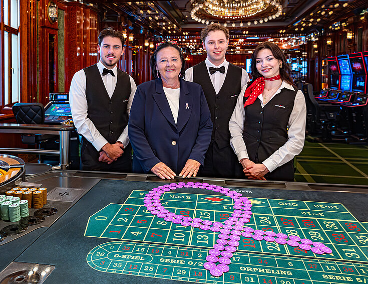 Pink Casino Night - Doris Kiefhaber Geschäftsführerin der Österr. Krebshilfe und der Aktion Pink Ribbon mit Croupière und Croupiers am Roulette-Tisch mit Pink Ribbon Symbol