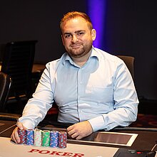 Pokermanager im Casino Linz, Thomas Wegenschimmel, sitzt an einem Pokertisch und lächelt in die Kamera.